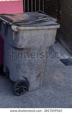 Filthy garbage bin on the side of a street on trash day
