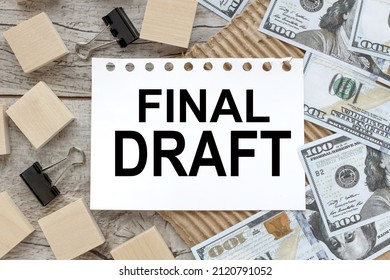 FINAL DRAFT text on white page near wooden blocks and black clips. there are a lot of dollar bills on the table