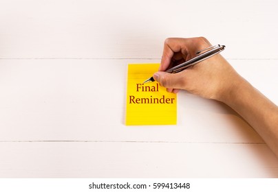 Final reminder on sticky note with hand writing on white wood