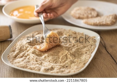 Final stage of coating meat in breadcrumbs while making schnitzels.