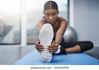 The Final Stretch Of The Race Always Decides The Winners. Shot Of An Attractive Young Woman Sitting Down And Doing Stretching Exercises On Her Gym Mat At Home.
