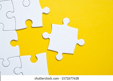 Final White Piece Is Lying Next To The Jigsaw Puzzle On Yellow Background. Concept Of Support, Setting, Adjustment, Repair, Achieving Goal.