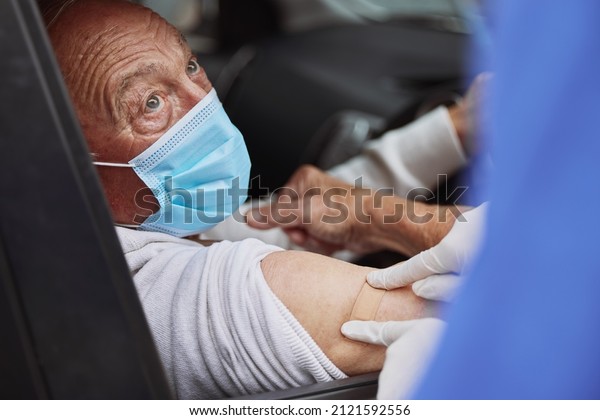 Finally fully vaccinated. Shot of an\
unrecognizable healthcare worker applying a band-aid to a patient\'s\
arm at a drive through vaccination\
site.