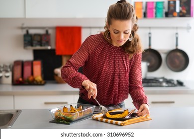 Finally Ready... An Elegant Woman Standing In A Kitchen Serves A Slice Of Roasted Pumpkin Onto A Plate To Serve To Her Thanksgiving Guests.