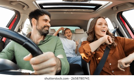 Finally, we are going on vacation. Happy family of three enjoying travelling by car, dancing to music and singing favorite song, panorama
