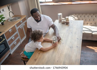 Finance Basics. Dark-skinned Bearded Man Talking To His Son About Saving Money