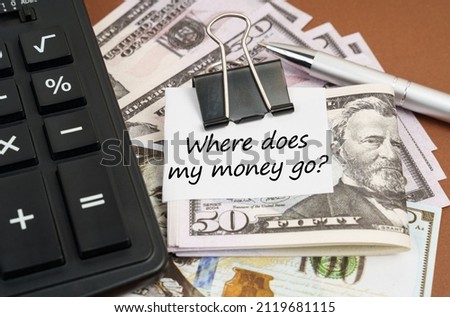 Finance and business concept. On a brown background lies a calculator and dollars on a clip with an inscription on paper - Where does my money go