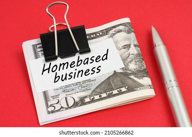 Finance and business concept. On a red background lies a pen and dollars clamped with a clip with the inscription on paper - Homebased business