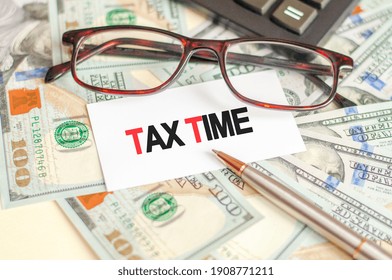 Finance and business concept. On the table are bills, glasses, pen and a sign on which it is written - Tax Time.
