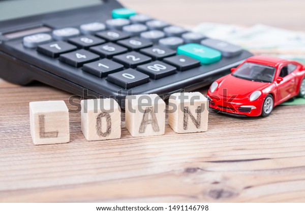 Finance and\
car loan, saving money for a car. Red car and euro banknotes.\
Calculator, euro money and House. Wooden cubes with word loan. Copy\
space for text. Loan payment car and house.\
