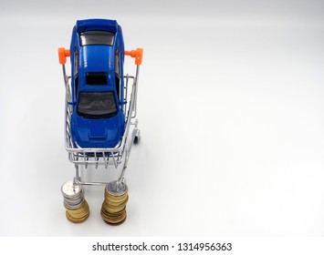 Finance commerce concept for car purchase loan. Image of blue car inside the shopping cart with money coin on white background.                              