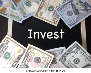 Finance Concept, top view of dollar notes written INVEST on chalkboard