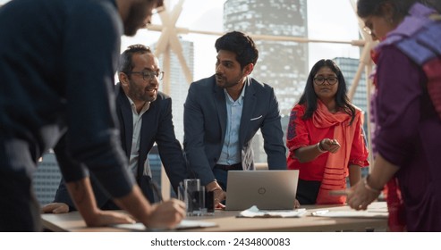 Finance Department Having a Meeting to Discuss a Project with Board Members. South Asian Colleague Using Laptop Computer, Working in Modern Office, Employees Having a Conversation in a Conference Room - Powered by Shutterstock