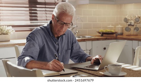 Finance, laptop and writing with senior man in kitchen of home for investment, pension or retirement. Computer, savings and tax with elderly person in apartment for payment of bill, debt or invoice - Powered by Shutterstock