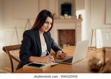 Finance manager. In a modern office, the workplace is a coworking space. The financier is a woman of European appearance. Works on a laptop and writes down the business strategy for the startup.