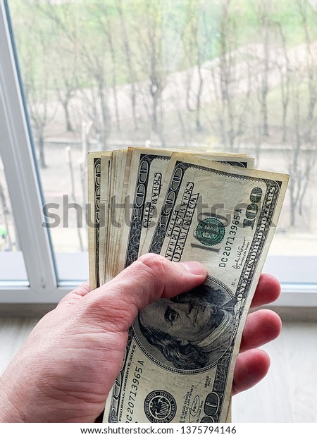 Finance money. Man holding a hundred\
dollars banknotes for rental or purchase\
flat