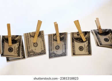 Finance, pegs and money laundering with bank notes on a washing line for white collar crime or fraud. Financial, cash and cleaning with usa dollar currency on a sky background for illegal payment