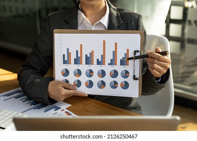 Finance Staff Holding Financial Graph Documents Presented To Executives And Attendees Via Videoconference, Meeting To Summarize The Operations Of All Departments. Videoconferencing Concept.