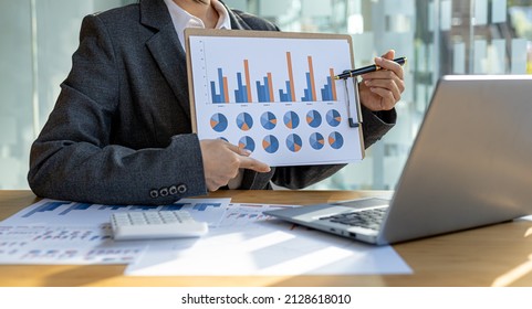 Finance Staff Holding Financial Graph Documents Presented To Executives And Attendees Via Videoconference, Meeting To Summarize The Operations Of All Departments. Videoconferencing Concept.