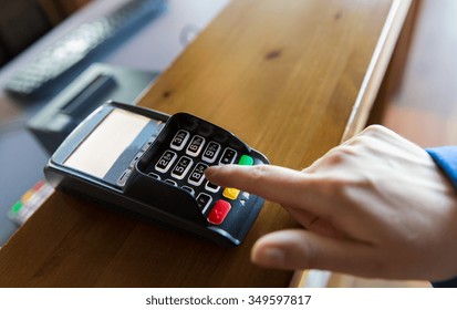 finance, technology, payment and people concept - close up of hand entering pin code to money terminal