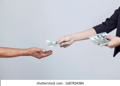 The Finance Woman Is Transferring Salary Or Bonus To Employee. Compensation Of Work. Woman's Hand Hold And Send US Dollar To Another Hand Isolated On White Background With Copy Space.