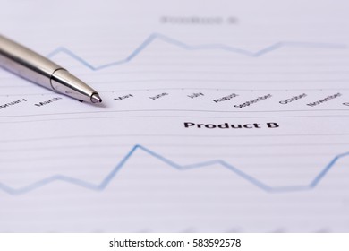 Financial accounting and marketing graphs analysis with a silver pen.