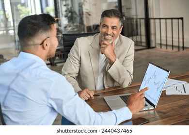 Financial advisor consulting smiling stock exchange market investor showing charts on laptop computer screen. Two business men analysts doing finance trading investment analysis working in office. - Powered by Shutterstock