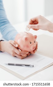 Financial Advisor Holding A Piggy Bank And Customer Inserting A Coin: Investments, Savings Plan And Retirement Fund Concept