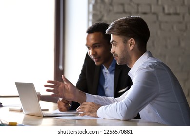 Financial advisor insurer speaking consulting african client looking at laptop making presentation, caucasian mentor teaching black intern, employees colleagues help discuss online computer project