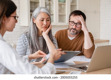 Financial advisor lawyer consulting mature middle-aged couple showing them debts, bunkruptcy, negative test results, mortgage, divorce certificate contract pension at home indoors - Powered by Shutterstock