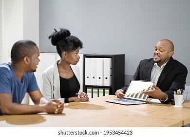 Financial Advisor Meeting With Couple Family Showing Graphs On Laptop