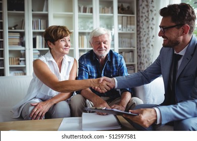 Financial Advisor Shaking Hands With Senior Woman In Living Room