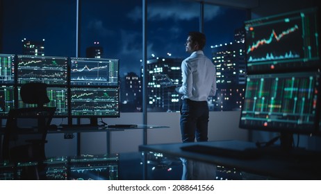 Financial Analyst Using Laptop Computer, Standing Next To Multi-Monitor Workstation With Real-Time Stocks, Commodities And Exchange Market Charts. Businessman Working In Broker Agency Office.