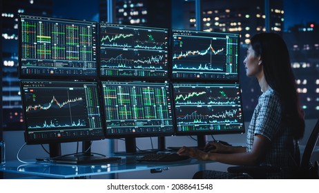 Financial Analyst Working on a Computer with Multi-Monitor Workstation with Real-Time Stocks, Commodities and Exchange Market Charts. Businesswoman at Work in Investment Broker Agency Office at Night. - Powered by Shutterstock