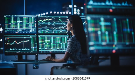 Financial Analyst Working Computer and Multi  Monitor Workstation and Real  Time Stocks  Commodities   Exchange Market Charts  Businesswoman at Work in Investment Broker Agency Office at Night 