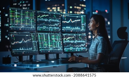 Financial Analyst Working on a Computer with Multi-Monitor Workstation with Real-Time Stocks, Commodities and Exchange Market Charts. Businesswoman at Work in Investment Broker Agency Office at Night.