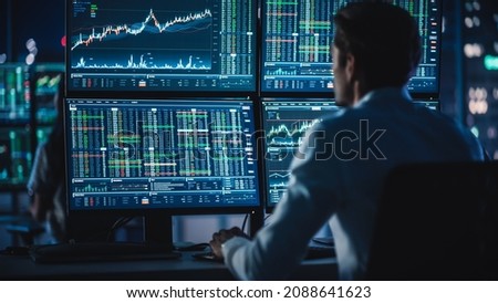 Financial Analysts and Day Traders Working on a Computers with Multi-Monitor Workstations with Real-Time Stocks, Commodities and Exchange Market Charts. Team of Brokers at Work in Agency.
