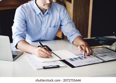 financial budget audit A male auditor is using a pen to write down budgets to trace the company's financial fraud.