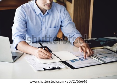 financial budget audit A male auditor is using a pen to write down budgets to trace the company's financial fraud.