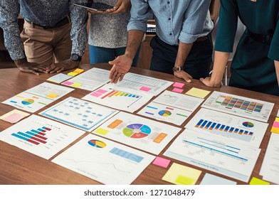 Financial and business documents on table with multiethnic hands working on it. Closeup business man and businesswoman hands understanding pie and bar graphs during meeting. - Powered by Shutterstock