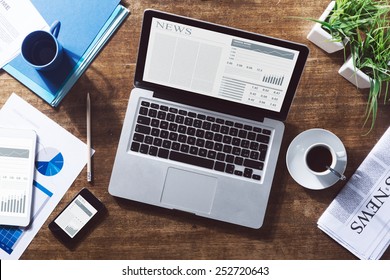 Financial business news online on a laptop with coffee and stationery - Powered by Shutterstock