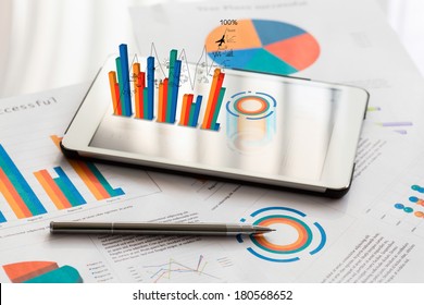 Financial charts on the table with tablet phone and pen - Powered by Shutterstock