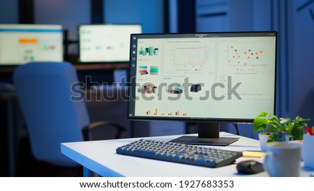 Financial company with nobody in it, place of work startup, workplace indoors concept. Interior of empty start up business office with modern design during night with graphics running on the desktop.