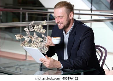 Financial concept. Make money on the Internet. Young attractive businessman having lunch and working in a cafe