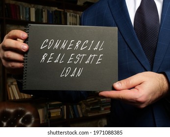 Financial Concept Meaning COMMERCIAL REAL ESTATE LOAN With Phrase On Blank Notepad In Hand. 
