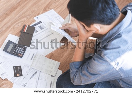 Financial concept, owe asian young man sitting suffer, stressed and confused by calculate expense from invoice credit card bill, no money to pay mortgage or loan. Debt, bankrupt or bankrupt people.