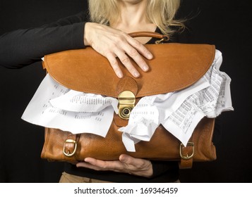 Financial concept photo showing a closeup of a female executive holding a briefcase overflowing with paperwork.