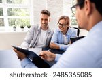 Financial consultant explaining new project investment to young couple in office. Real estate agent discussing mortgage options with family. Mortgage loan consultation with financial advisor.