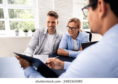 Financial consultant explaining new project investment to young couple in office. Real estate agent discussing mortgage options with family. Mortgage loan consultation with financial advisor. - Powered by Shutterstock