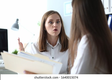 Financial department data verification and error. Woman expresses surprise at news that her colleague is telling. Detection data inconsistency in workplace. Girl holds an open folder with documents. - Powered by Shutterstock